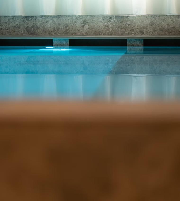 Piscina interna con pareti di marmo e acqua azzurra riflettente.
